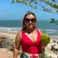 Foto de Amanda Soares sorrindo em uma praia, usando maiô vermelho e segurando um coco